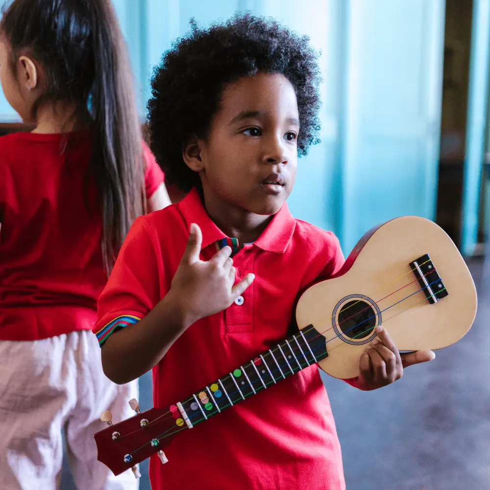 Enfant qui tient un ukulélé pour apprendre le ukulélé en cours collectif