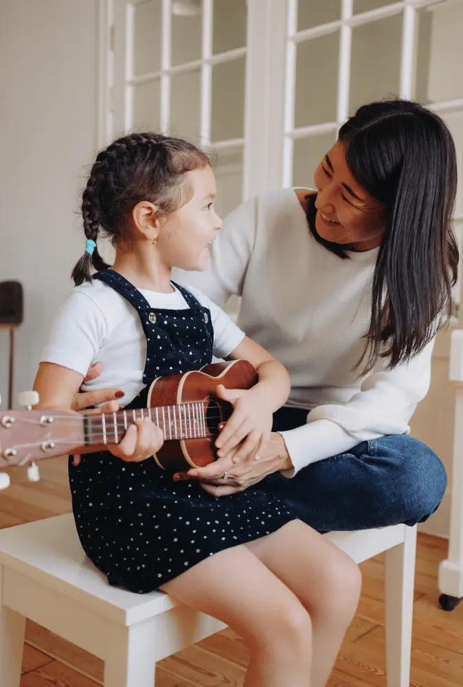 Parent et enfant qui apprennent le ukulélé en ligne ensemble