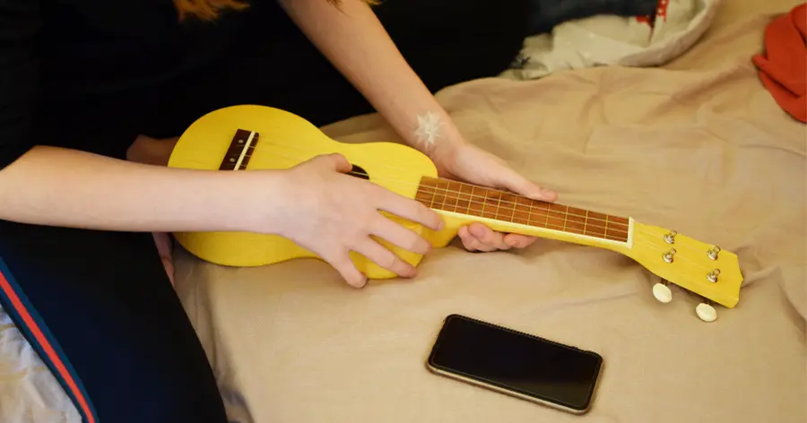 Enfant qui apprend comment accorder un ukulélé avec une application mobile